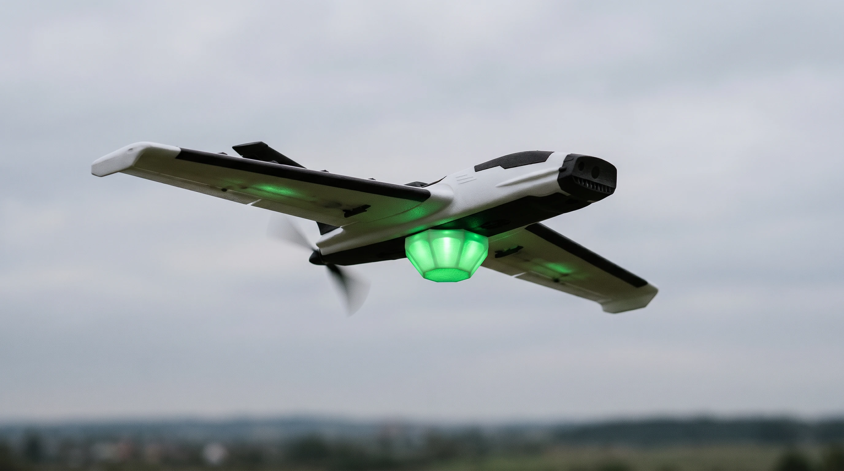 Fixed-wing UAS concept carrying a green-illuminated Arena Go! capsule