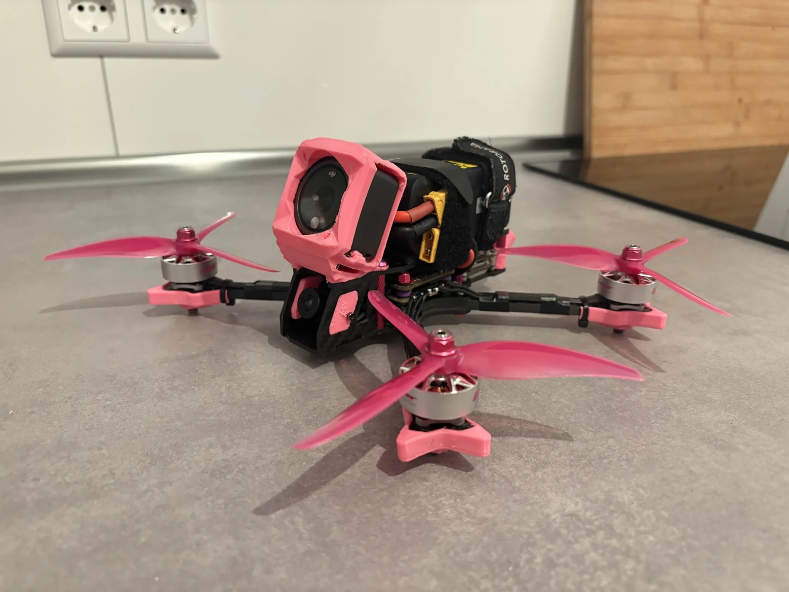 Pink-accented FPV drone with an action camera mounted above the FPV camera