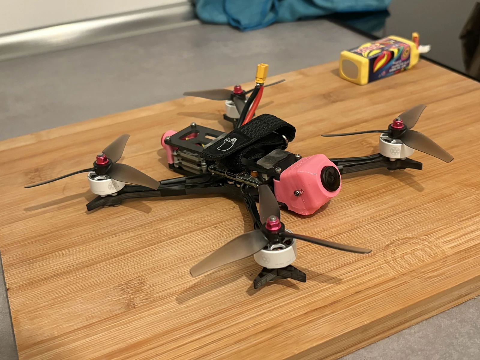 Assembled FPV quadcopter with a pink camera housing on a wooden surface