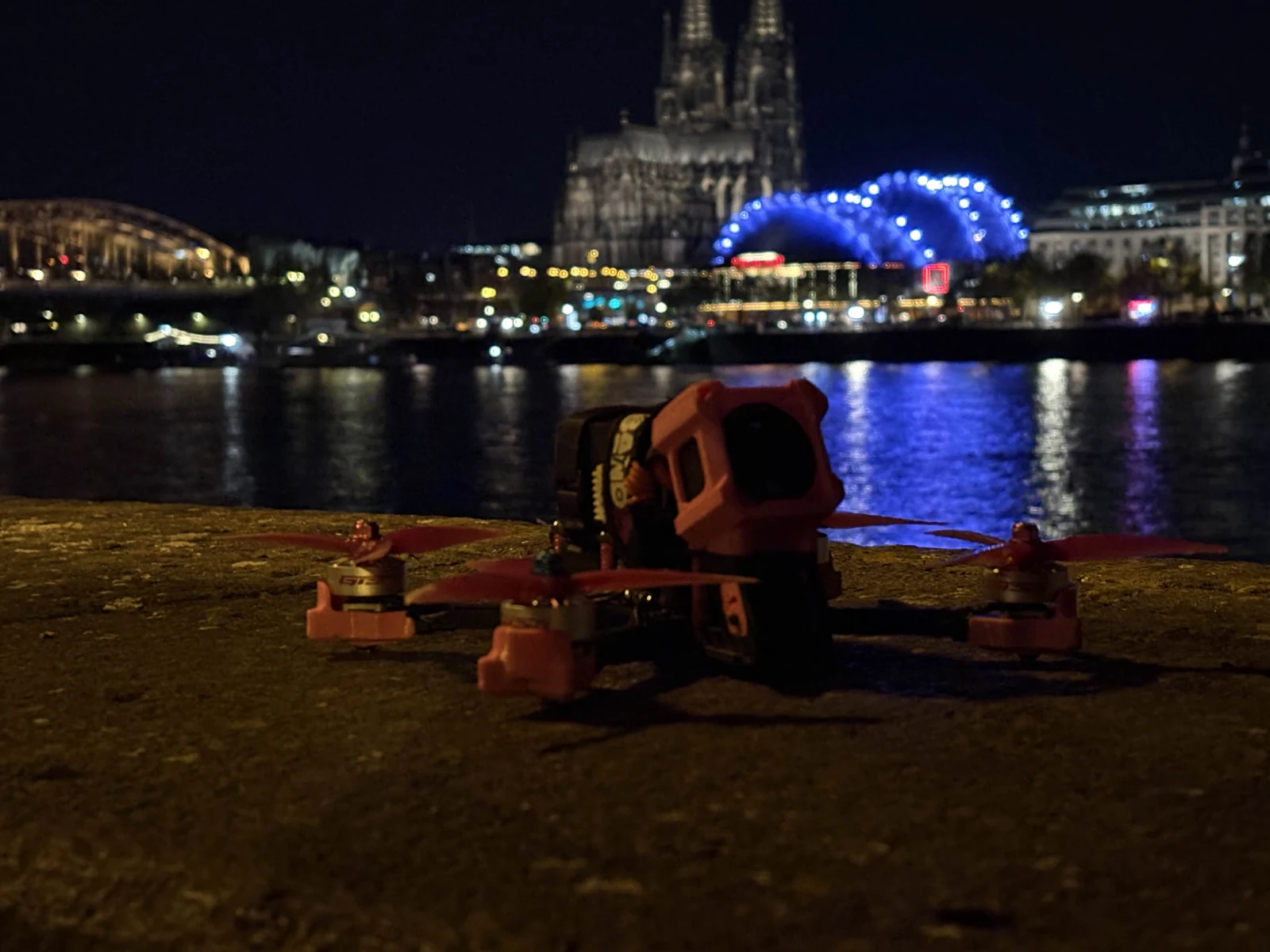 FPV quadcopter beside a river with city lights in the background