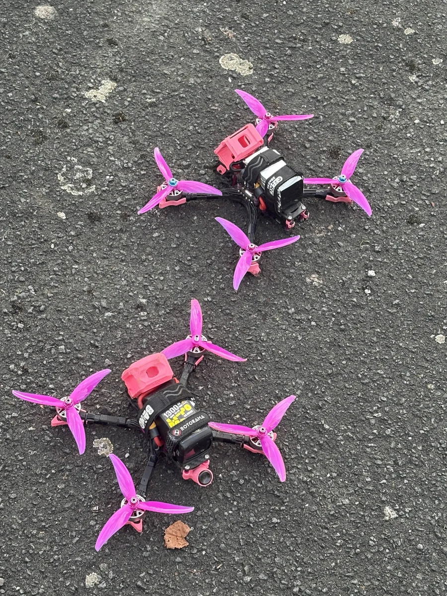 Overhead photograph of two FPV drones with pink components